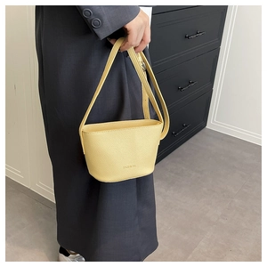 Close-up of bright yellow bucket bag featuring lychee grain texture and fashion logo