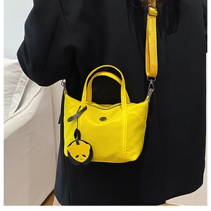 Détail d'un sac bandoulière en nylon jaune vif avec pendentif panda et sangle large