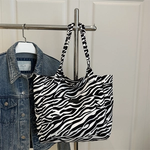 Zebra print canvas tote bag with outer pocket shown hanging on a metal hanger
