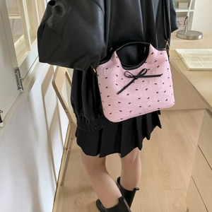 Bolso saco rosa con lazos negros lucido por modelo para un look de verano moderno