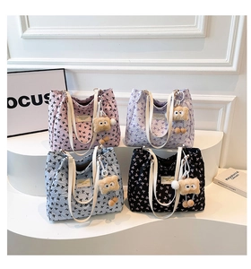 Détail de sacs fourre-tout en quatre couleurs avec motifs nœuds et breloques ours