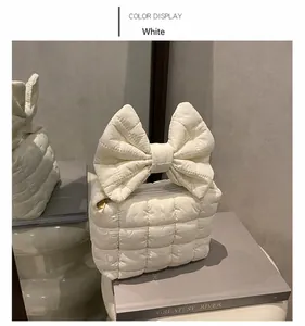Detail of white quilted nylon makeup bag with a large decorative bow and gold zipper