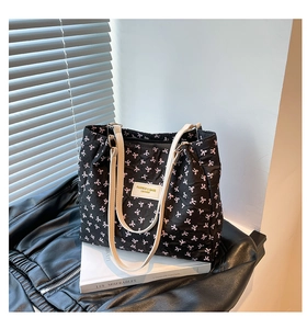 Detalle de bolso tote acolchado negro con lazos rosas y correas finas en color blanco crema