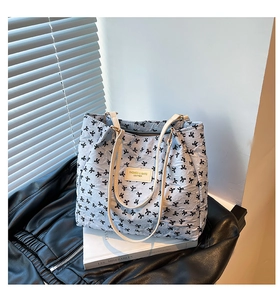 Detalle del bolso tote azul claro con estampados de lazos negros y asas de cuero