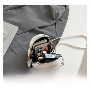 Interior capacity of the minimalist cream crossbody bag showing daily items and phone