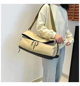 Détail du sac bandoulière multi-poches en nylon beige avec une sangle verte