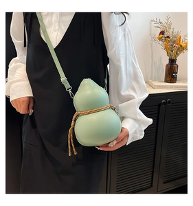Detail of light green gourd-shaped crossbody bag with decorative woven rope on a model