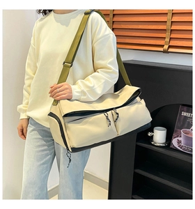 Détail d'un grand sac bandoulière beige avec sangles vertes et poches à cordon tressé
