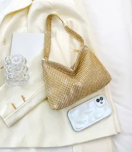 Detail einer funkelnden goldenen Strass-Hobo-Tasche auf einem schicken beigen Blazer