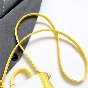 Detail of yellow PU shoulder strap and white handbag featuring red cherry prints