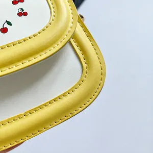Close-up of contrast leather bag with cherry pattern and yellow stitching detail