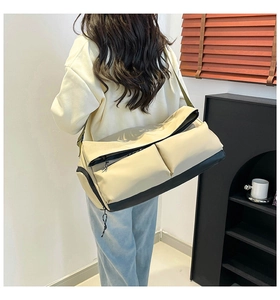 Dettaglio di borsa sportiva beige e nera con ampie tasche frontali a patta sulla modella