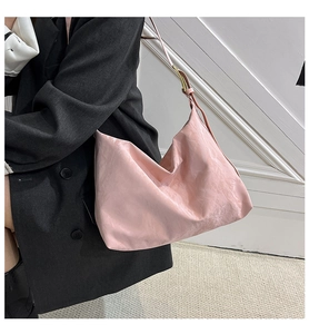 Detail of light pink tote bag with pleated texture shown on a black blazer outfit