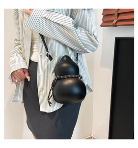 Unique gourd-shaped black crossbody bag with woven rope detail shown on model