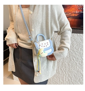 Detail of mini crossbody bag with cherry embroidery and plush moon charm accessory
