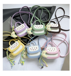 Detail showing colorful mini crossbody bags with cherry prints and moon plush pendants