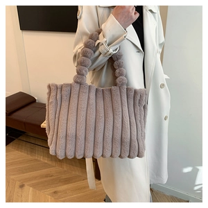 Detail of plush tote bag featuring unique fuzzy ball handle and vertical stripe texture