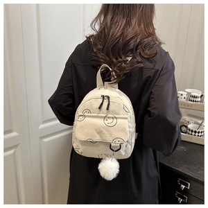 Close-up of beige corduroy mini backpack with smiley face and plush white pompom