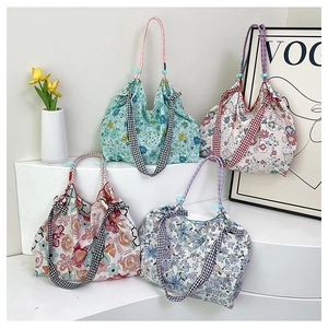 Floral canvas tote bags with plaid bow detail and woven handles on a display stand