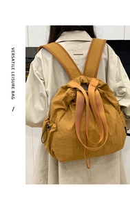 Mochila mostaza con cordón mostrada en una modelo con una gabardina color beige