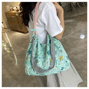 Detail of floral tote bag showing the unique plaid strap and colorful rope handle