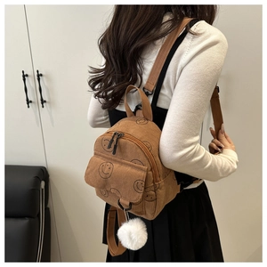Detail of mini brown corduroy backpack with smiley prints and white pom-pom pendant