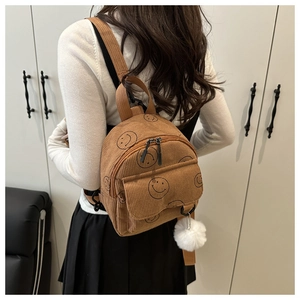 Detailansicht eines braunen Cord-Minirucksacks mit Smiley-Print und Plüschanhänger