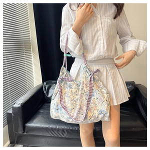 Detail of floral tote bag with purple plaid bow and woven rope straps in home setting