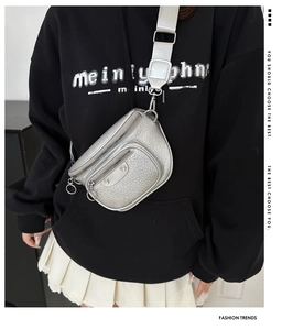 Detail of silver metallic crossbody bag with crocodile texture and wide fabric strap