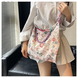 Detailed close-up of floral canvas tote bag with decorative red checkered strap