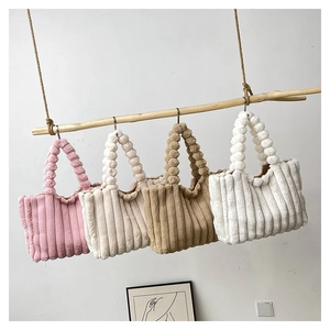 Detailed close-up of plush striped tote bags with unique fuzzy ball handle design