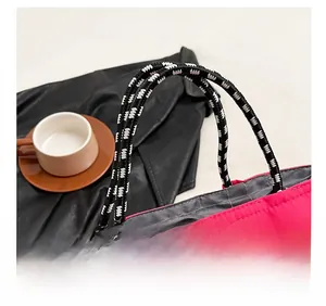 Detail of hot pink tote bag with black and white woven rope handles and gray lining