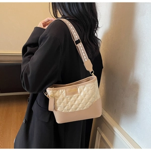 Dettaglio della borsa hobo trapuntata beige con cuciture a contrasto e tracolla tessuta
