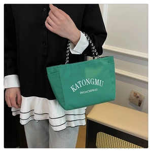 Close-up of green waterproof nylon tote bag with striped handles and side pocket detail