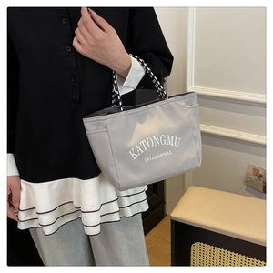 Close-up of a light grey waterproof nylon tote with white lettering and woven handles