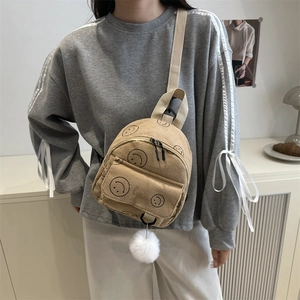 Mini khaki corduroy backpack with black smiley face and white plush pompom charm