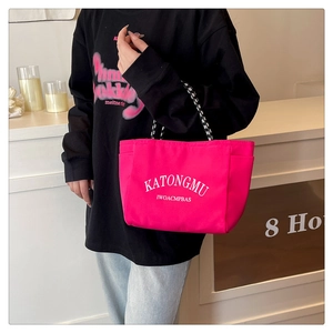 Detail of hot pink nylon tote bag with monochrome braided handles and white graphic print