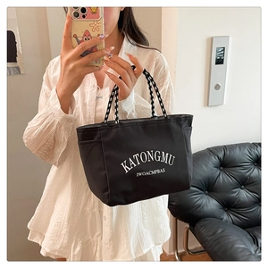 Detail of waterproof nylon tote bag with white lettering and woven rope handle
