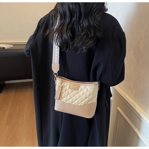 Vista dettagliata della tracolla ampia in jacquard su una borsa beige trapuntata