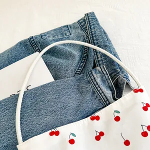 Detail shot of the cherry print canvas bag showing soft rope handles and fabric texture