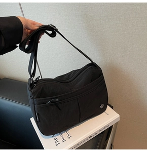 Détail de la bandoulière réglable et du nylon imperméable durable de ce sac noir