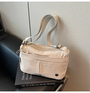 Détail macro du sac bandoulière beige en nylon avec poches zippées et sangle large