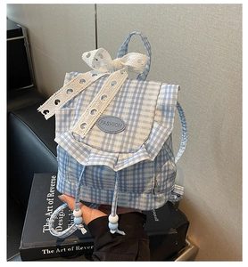 Detail of blue plaid backpack with large white lace bow and ruffled edge decoration