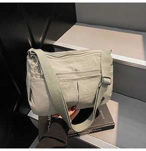 Détail du sac bandoulière en nylon vert sauge avec plusieurs poches et sangle réglable