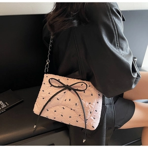 Detail der rosa Schultertasche mit Schleifenmuster, Bandschmuck und silberner Metallkette