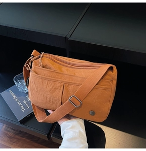 Vue détaillée du sac bandoulière orange en nylon imperméable avec plusieurs poches zippées