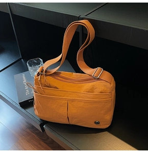 Détail d'un sac bandoulière en nylon orange brûlé avec plusieurs poches zippées fonctionnelles
