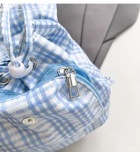 Detailed close-up of smooth metal zipper and drawstring on blue checkered ruffle backpack