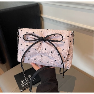Detail der rosa Plissee-Tasche mit großer schwarzer Schleife und silberner Kette