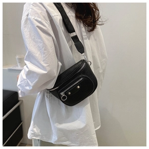 Close-up of black lychee grain leather waist bag with silver zippers and wide nylon strap